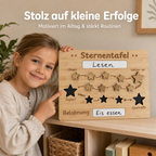 Kind zeigt stolz eine Sternentafel aus Holz für Routinen, Motivation und kleine Erfolge